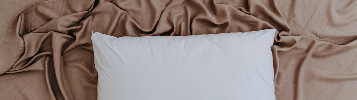 white pillow on brown sheets